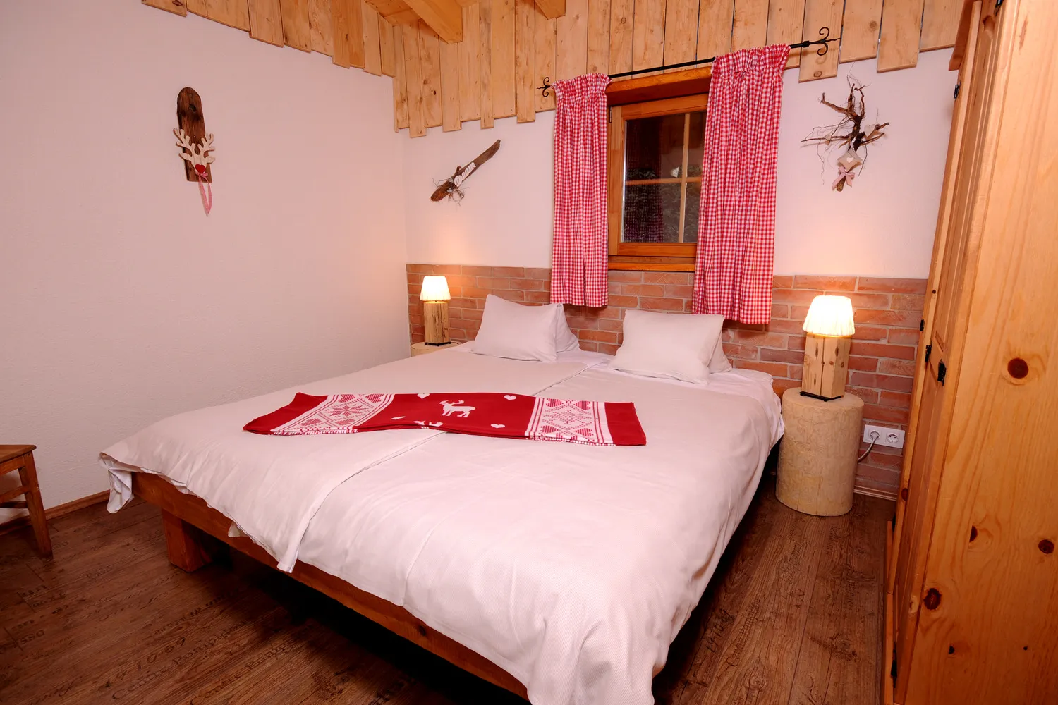 Schlafzimmer mit Doppelbett und roter Decke im Almchalet Dorfblick