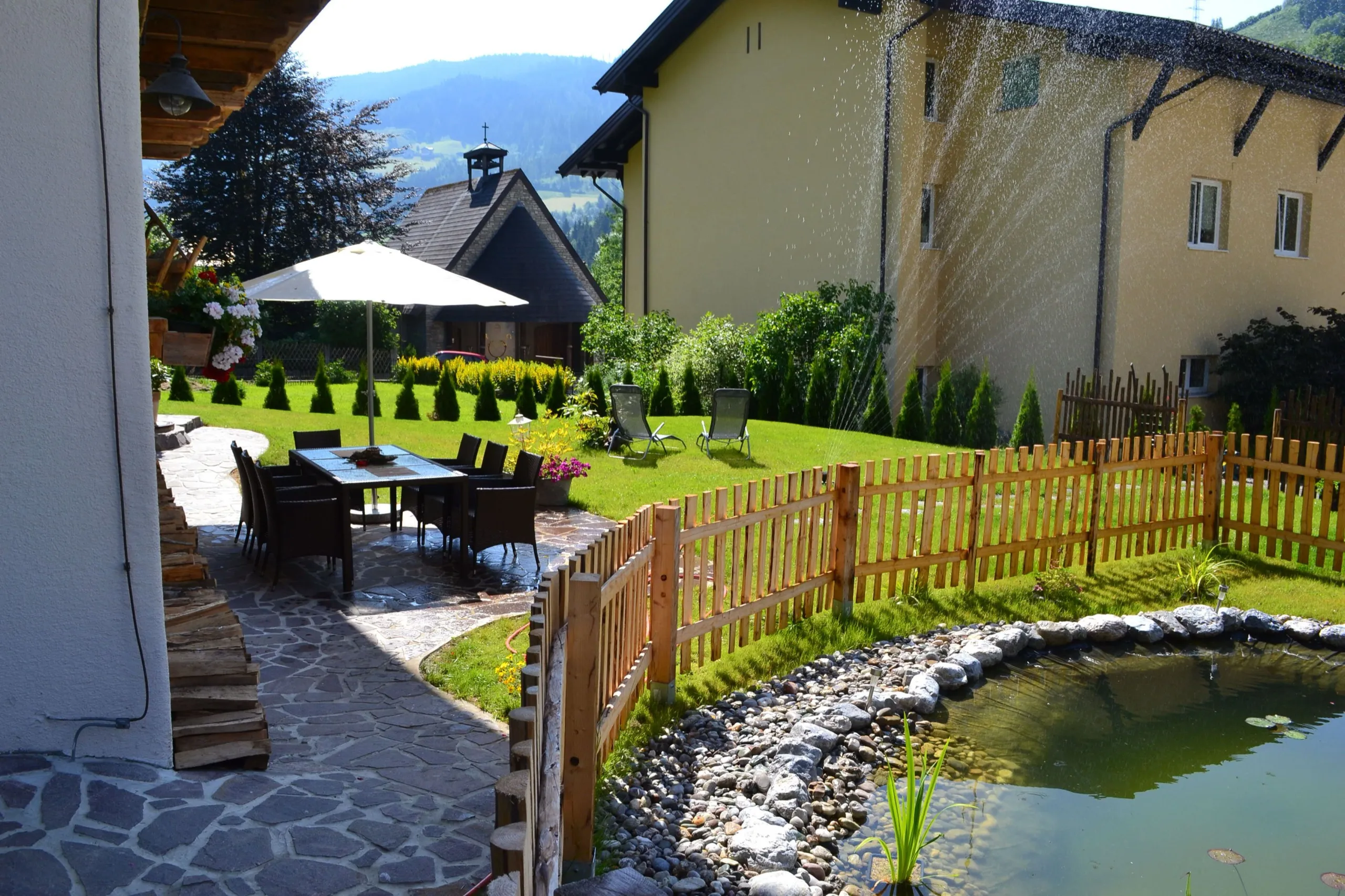 Garten mit Sitzgruppe, Sonnenschirm und Teich am Almchalet am Hochkönig
